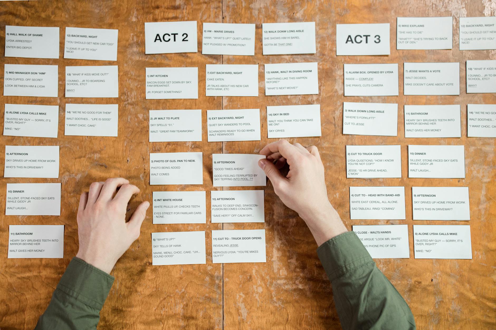 top view of man putting cards with text of acts of a play on a table